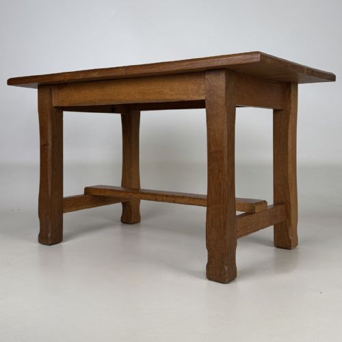 fig 1. A rectangular solid oak coffee table featuring simple square legs joined by low side stretchers in an Arts and Crafts style.