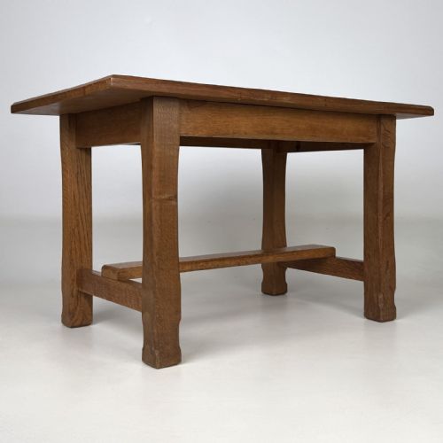 fig 7. A rectangular solid oak coffee table featuring simple square legs joined by low side stretchers in an Arts and Crafts style.