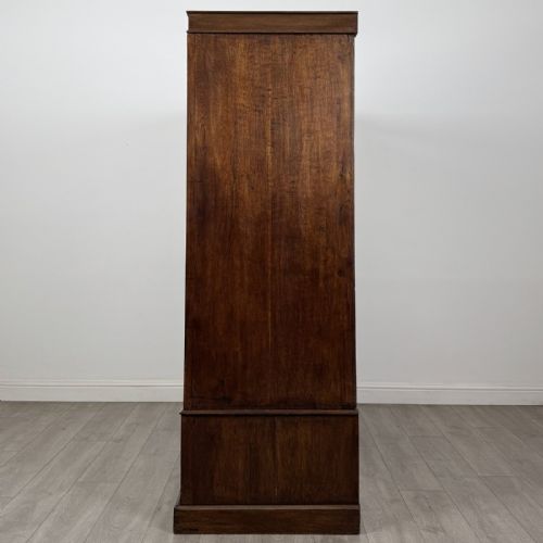 fig 2. A tall dark oak Edwardian wardrobe featuring double panelled doors above a single full-width base drawer with brass drop handles.