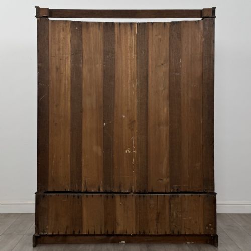 fig 4. A tall dark oak Edwardian wardrobe featuring double panelled doors above a single full-width base drawer with brass drop handles.