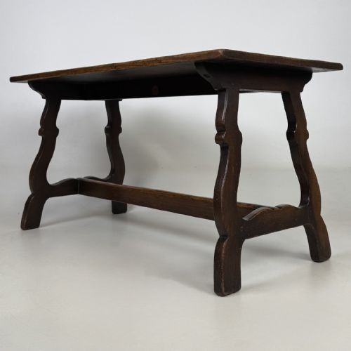 fig 1. A dark brown oak low coffee table featuring a rectangular plank top supported by shaped trestle end legs joined by a low central stretcher.
