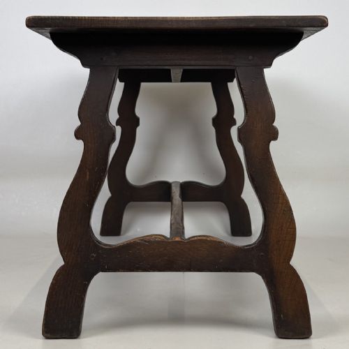 fig 2. A dark brown oak low coffee table featuring a rectangular plank top supported by shaped trestle end legs joined by a low central stretcher.
