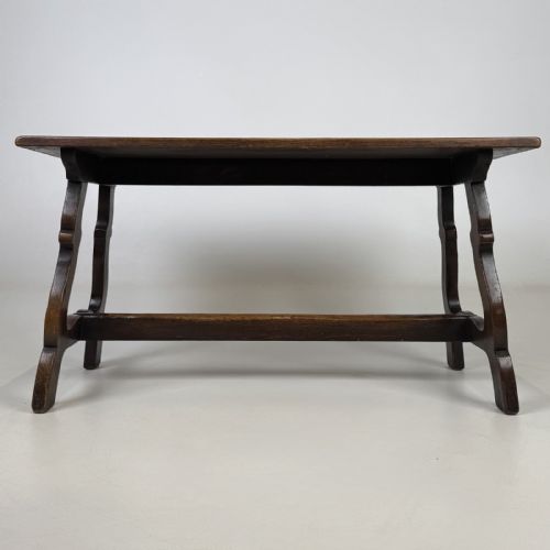 fig 4. A dark brown oak low coffee table featuring a rectangular plank top supported by shaped trestle end legs joined by a low central stretcher.