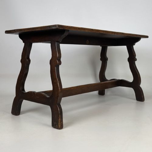 fig 7. A dark brown oak low coffee table featuring a rectangular plank top supported by shaped trestle end legs joined by a low central stretcher.