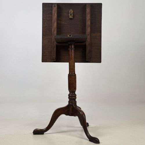 fig 4. An antique Georgian mahogany tilt-top tripod table featuring a square top supported by a turned central column and three cabriole legs with pad feet.