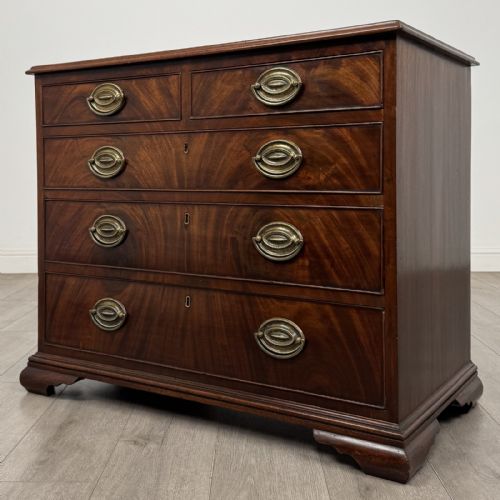 fig 1. An 18th-century Georgian dark mahogany chest of drawers featuring a two-over-three drawer arrangement with oval brass handles and bracket feet.