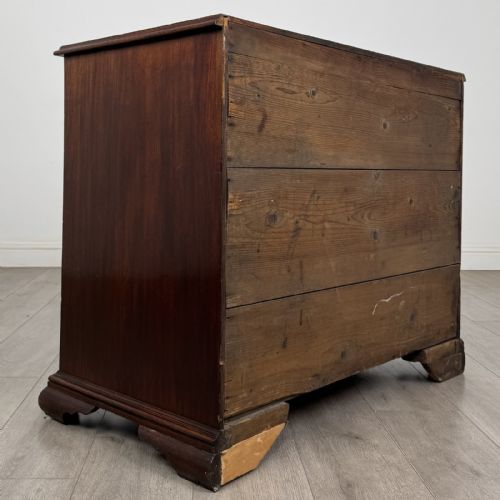 fig 3. An 18th-century Georgian dark mahogany chest of drawers featuring a two-over-three drawer arrangement with oval brass handles and bracket feet.