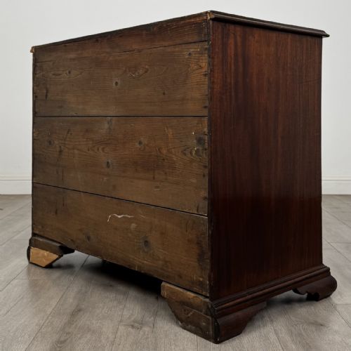 fig 5. An 18th-century Georgian dark mahogany chest of drawers featuring a two-over-three drawer arrangement with oval brass handles and bracket feet.
