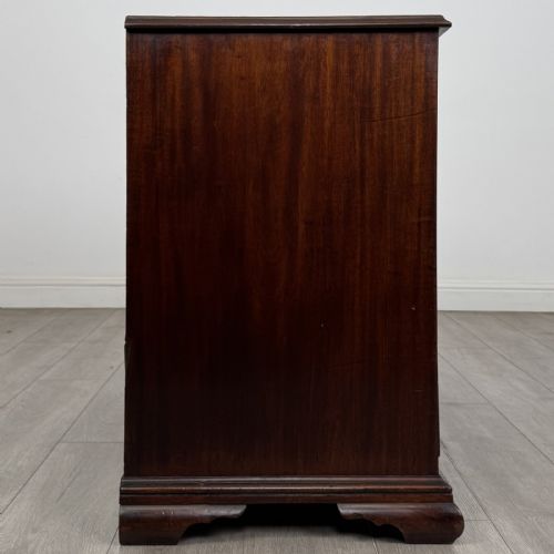 fig 6. An 18th-century Georgian dark mahogany chest of drawers featuring a two-over-three drawer arrangement with oval brass handles and bracket feet.