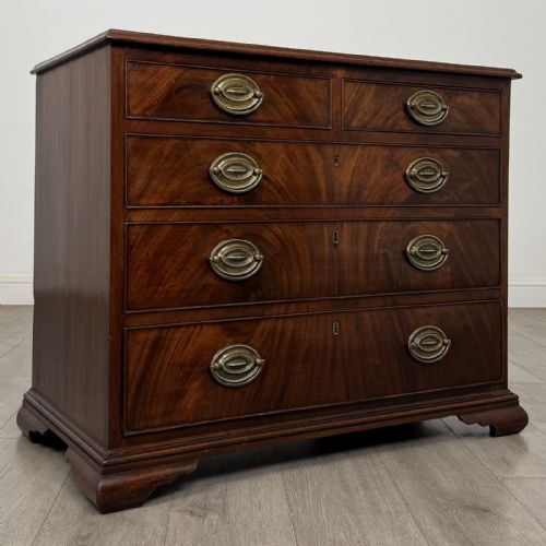 fig 7. An 18th-century Georgian dark mahogany chest of drawers featuring a two-over-three drawer arrangement with oval brass handles and bracket feet.