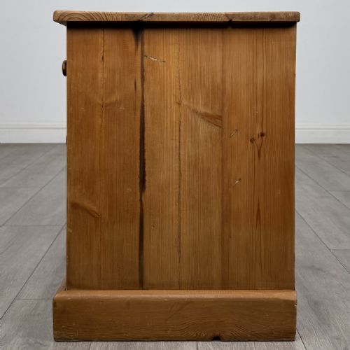 fig 2. A 20th-century pine chest of drawers featuring nine multi-sized drawers with dark turned wooden knobs arranged on a solid plinth base.