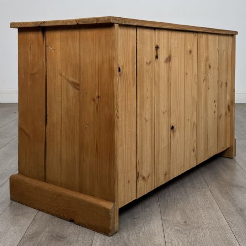fig 3. A 20th-century pine chest of drawers featuring nine multi-sized drawers with dark turned wooden knobs arranged on a solid plinth base.