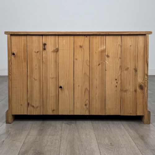 fig 4. A 20th-century pine chest of drawers featuring nine multi-sized drawers with dark turned wooden knobs arranged on a solid plinth base.