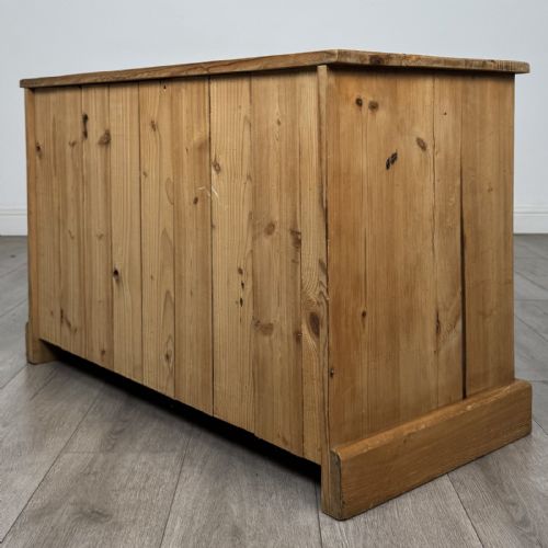 fig 5. A 20th-century pine chest of drawers featuring nine multi-sized drawers with dark turned wooden knobs arranged on a solid plinth base.