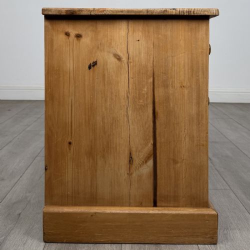 fig 6. A 20th-century pine chest of drawers featuring nine multi-sized drawers with dark turned wooden knobs arranged on a solid plinth base.