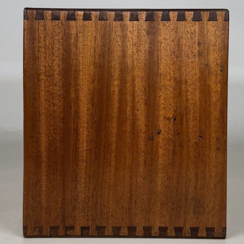 fig 6. An early 20th-century mahogany tabletop cabinet featuring five graduated drawers with dark round pull handles and a keyhole on the lowest drawer.