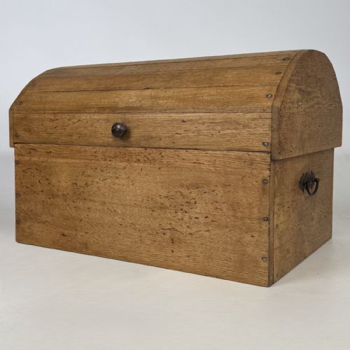 fig 1. A small light oak storage chest featuring a curved domed lid, metal stud details along the side edges, and a central wooden knob on the front.