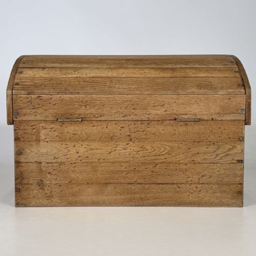 fig 4. A small light oak storage chest featuring a curved domed lid, metal stud details along the side edges, and a central wooden knob on the front.
