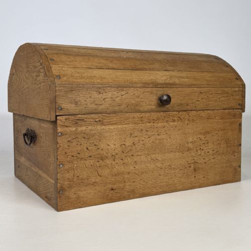 fig 7. A small light oak storage chest featuring a curved domed lid, metal stud details along the side edges, and a central wooden knob on the front.