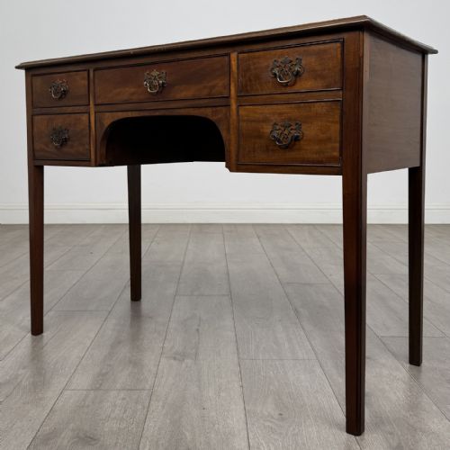 fig 1. A small Georgian style mahogany writing desk featuring five drawers with brass handles and straight tapered legs.