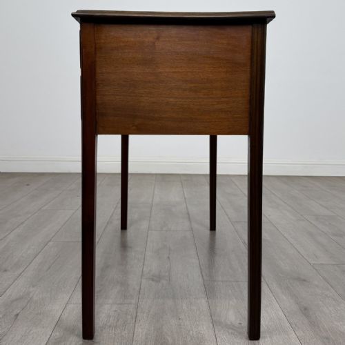 fig 2. A small Georgian style mahogany writing desk featuring five drawers with brass handles and straight tapered legs.