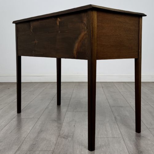 fig 5. A small Georgian style mahogany writing desk featuring five drawers with brass handles and straight tapered legs.