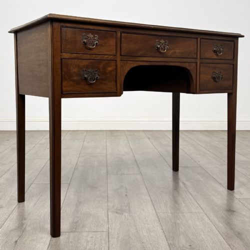 fig 7. A small Georgian style mahogany writing desk featuring five drawers with brass handles and straight tapered legs.
