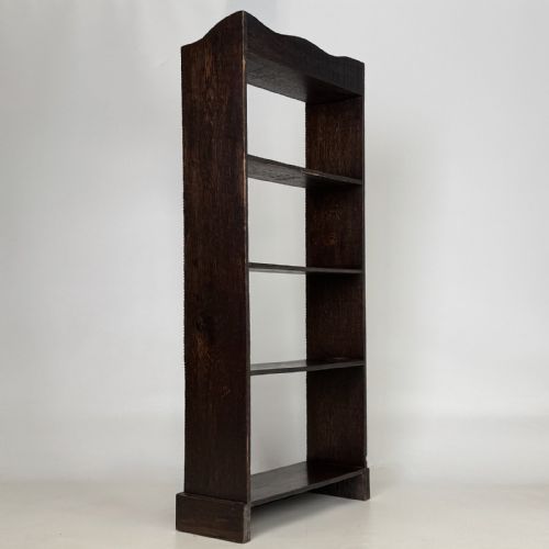 fig 4. A tall and narrow early 20th-century dark oak open bookcase with five shelf levels and a shaped top gallery.