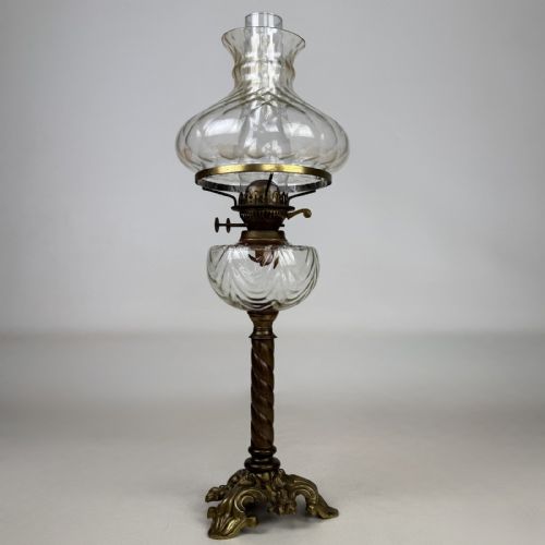 fig 2. A 19th-century brass oil lamp featuring a cast footed base, a spiral twisted column, a clear swirled glass reservoir, and a matching swirled glass shade.