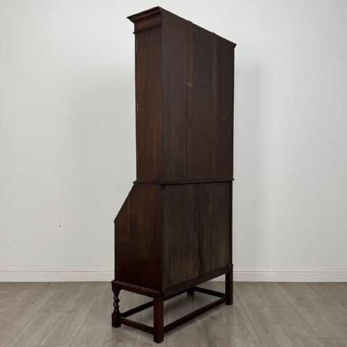 fig 4. A dark oak bureau bookcase with upper glazed doors, a fall-front desk flap, lower drawers, and turned barley twist legs.