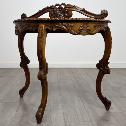 fig 1. A semicircular carved wooden demi-lune console table featuring cabriole legs, an ornate raised gallery back with carved floral motif, and a gadrooned top edge.
