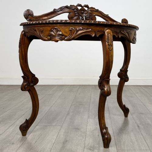 fig 5. A semicircular carved wooden demi-lune console table featuring cabriole legs, an ornate raised gallery back with carved floral motif, and a gadrooned top edge.