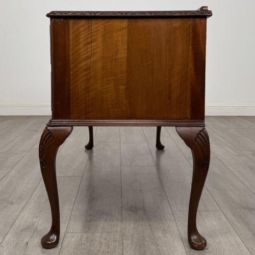 fig 2. A Queen Anne style burr walnut writing desk featuring a serpentine front, five drawers with brass handles, and carved cabriole legs.