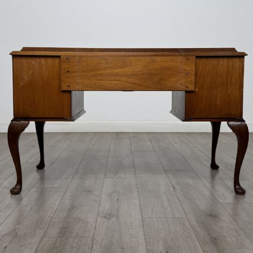 fig 4. A Queen Anne style burr walnut writing desk featuring a serpentine front, five drawers with brass handles, and carved cabriole legs.