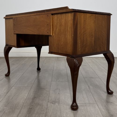 fig 5. A Queen Anne style burr walnut writing desk featuring a serpentine front, five drawers with brass handles, and carved cabriole legs.
