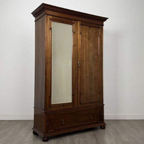 fig 7. An antique early 20th-century walnut double wardrobe featuring a full-length mirror door, panelled right door, geometric mouldings, and a single lower drawer.