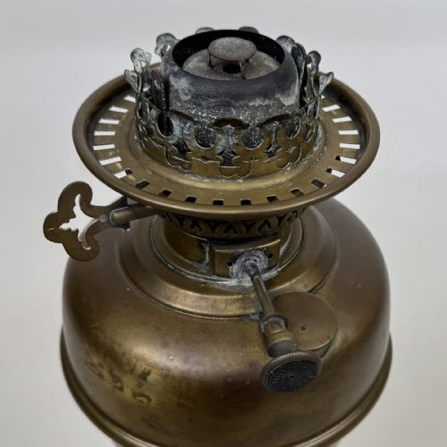 fig 3. An antique brass oil lamp featuring a reeded pedestal column, a clear glass chimney, and a frilled frosted glass shade decorated with floral etching.