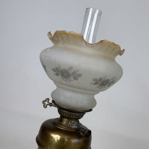 fig 5. An antique brass oil lamp featuring a reeded pedestal column, a clear glass chimney, and a frilled frosted glass shade decorated with floral etching.