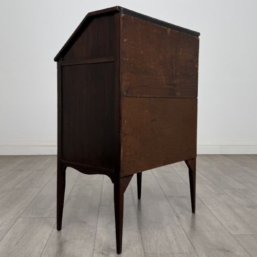 fig 3. An Edwardian dark mahogany bureau featuring a slant-front writing lid, a single drawer with brass drop handles, open lower compartment with arches, and tapered legs.