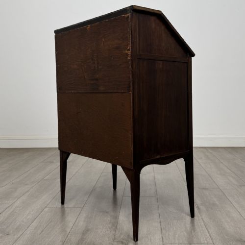 fig 5. An Edwardian dark mahogany bureau featuring a slant-front writing lid, a single drawer with brass drop handles, open lower compartment with arches, and tapered legs.