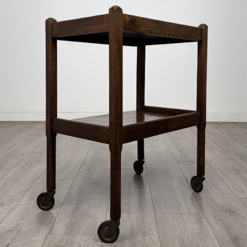 fig 3. A dark oak two-tier tea trolley featuring beaded moulding along the edges and small dark castors on four straight legs.