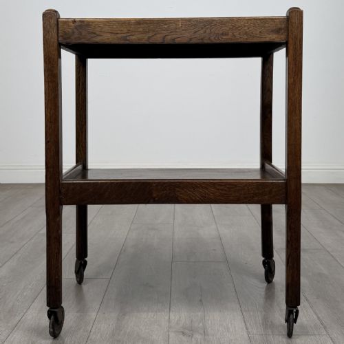 fig 4. A dark oak two-tier tea trolley featuring beaded moulding along the edges and small dark castors on four straight legs.