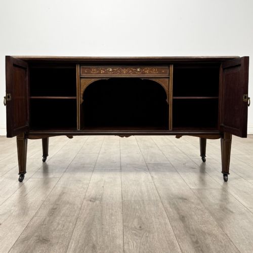 fig 1. An Edwardian inlaid mahogany sideboard with cherub marquetry panels, a central arched alcove, drawer, and square tapered legs with castors.
