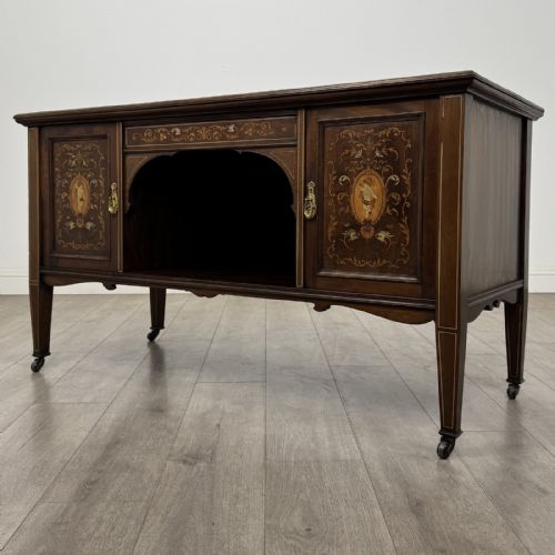 fig 2. An Edwardian inlaid mahogany sideboard with cherub marquetry panels, a central arched alcove, drawer, and square tapered legs with castors.