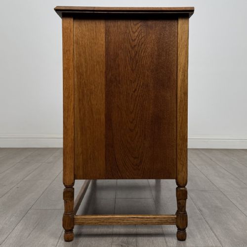fig 2. An antique oak chest of drawers featuring two short drawers above two long drawers, metal drop handles, turned legs, and a lower stretcher rail.
