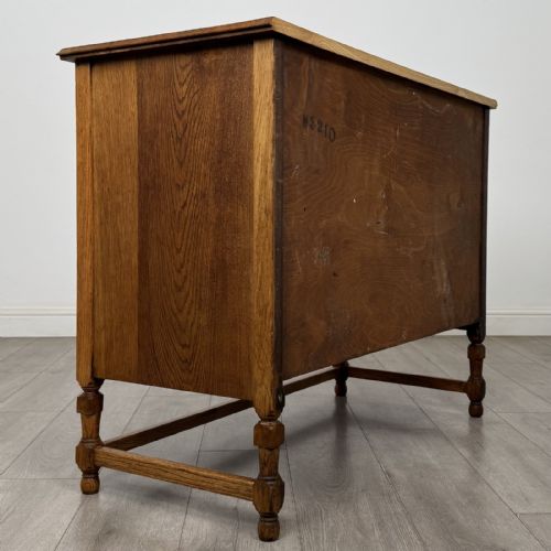 fig 3. An antique oak chest of drawers featuring two short drawers above two long drawers, metal drop handles, turned legs, and a lower stretcher rail.