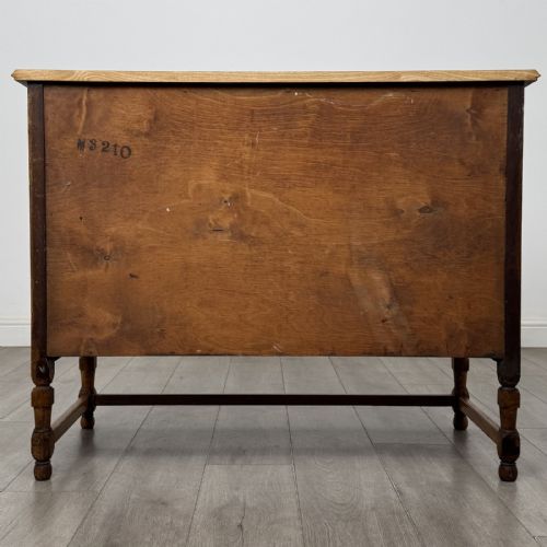 fig 4. An antique oak chest of drawers featuring two short drawers above two long drawers, metal drop handles, turned legs, and a lower stretcher rail.
