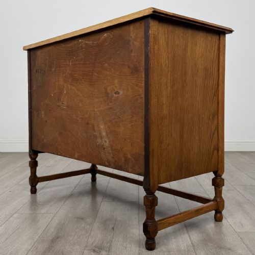 fig 5. An antique oak chest of drawers featuring two short drawers above two long drawers, metal drop handles, turned legs, and a lower stretcher rail.