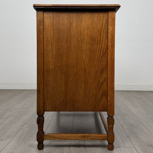 fig 6. An antique oak chest of drawers featuring two short drawers above two long drawers, metal drop handles, turned legs, and a lower stretcher rail.