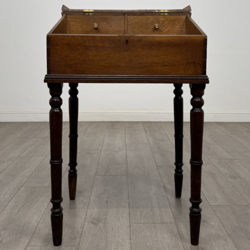 fig 1. A small dark oak Victorian clerks desk with a sloped hinged lid raised on tall turned legs.